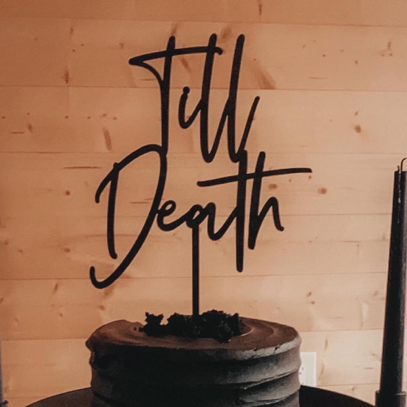 May include: Black cake topper with the words "Till Death" written in a cursive script.