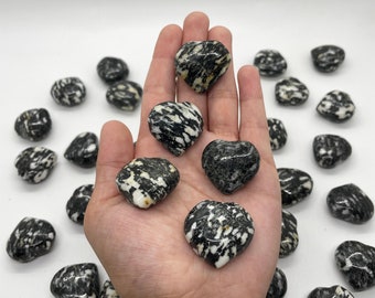 May include: A collection of black and white heart-shaped tumbled stones. The stones have a unique marbled pattern.