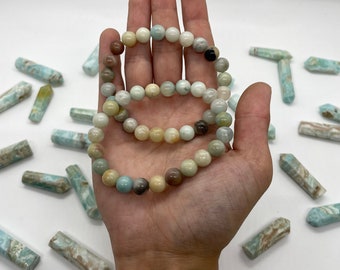 May include: Three stacked bracelets made of round, multi-colored, semi-precious stones. The bracelets are made of light blue, brown, white, and pink stones.