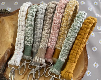 May include: A set of eight colorful crocheted keychains with silver key rings. The keychains are made of cotton rope and feature a variety of colors, including white, green, beige, pink, yellow, and brown.
