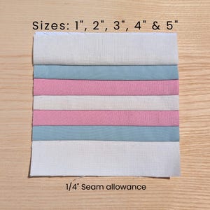 May include: A fabric swatch with alternating bands of white, light blue, and pink. The text "Sizes: 1", 2", 3", 4" & 5"" is at the top. The text "1/4" Seam allowance" is at the bottom. The fabric is on a light wood surface.
