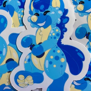 May include: A blue and yellow cartoon character sticker with a smiling face and a spotted body. The character is holding a blue and black object in its hands.