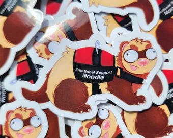 May include: A collection of stickers featuring a cartoon ferret with a tan body and brown markings. The ferret wears a black harness with the words "Emotional Support Noodle". The stickers have a white border and are scattered across the image.