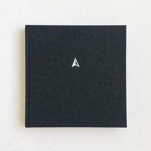 May include: A black hardcover journal with a white compass symbol on the front.