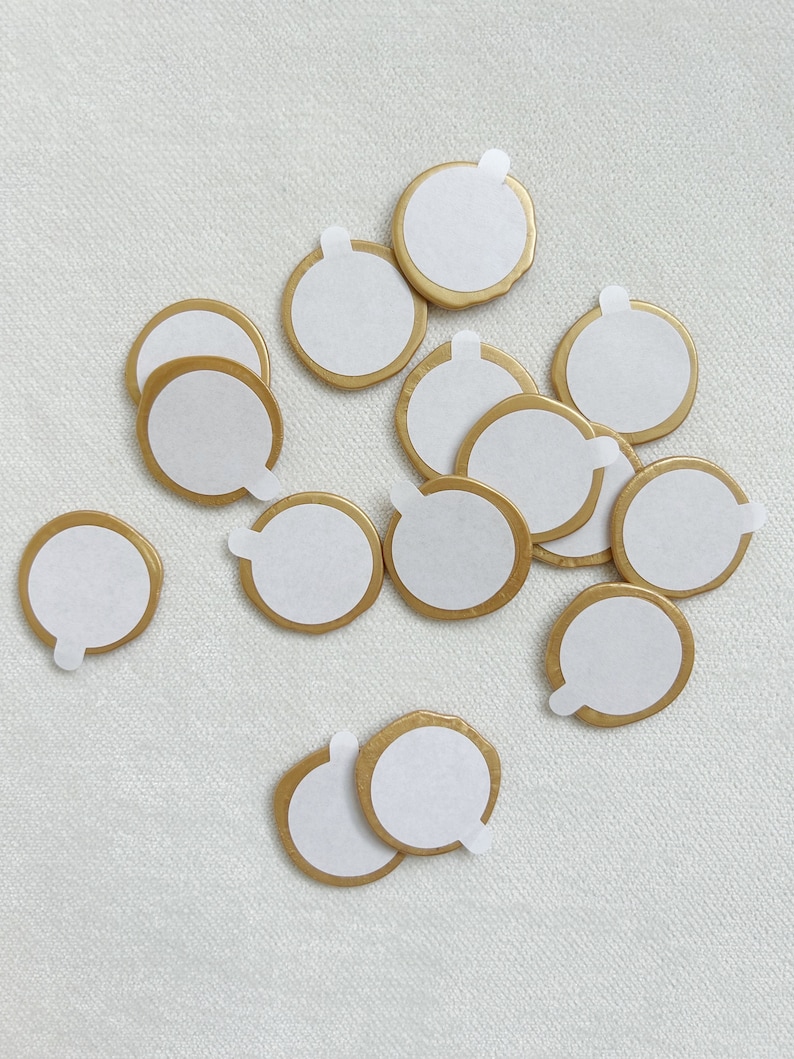 May include: A collection of 14 gold-rimmed, round, adhesive stickers with white centers. The stickers are arranged in a random pattern on a white surface.