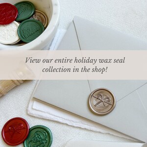 May include: A collection of holiday wax seals in a white marble bowl. The seals are in various colors, including red, green, and gold. The seals feature designs such as a snowflake, a Christmas tree, and a bow. The text "View our entire holiday wax seal collection in the shop!" is displayed on a banner above the bowl.