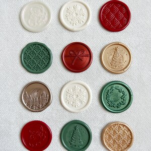 May include: Twelve round wax seals with various Christmas-themed designs. The seals are in red, green, gold, and white.