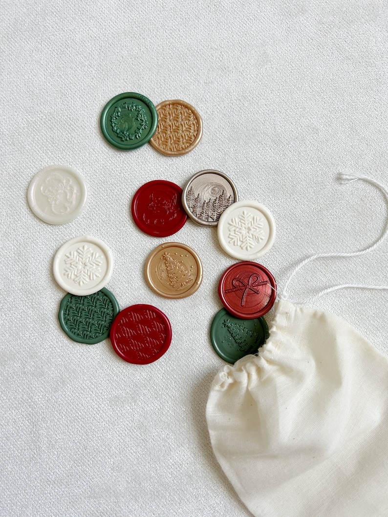 May include: A collection of 12 assorted wax seals in a variety of colors and designs, including green, red, gold, and white. The seals are in a small white drawstring bag.