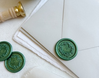 May include: Green wax seals with a floral design, some are in a white bowl and others are on a white surface.
