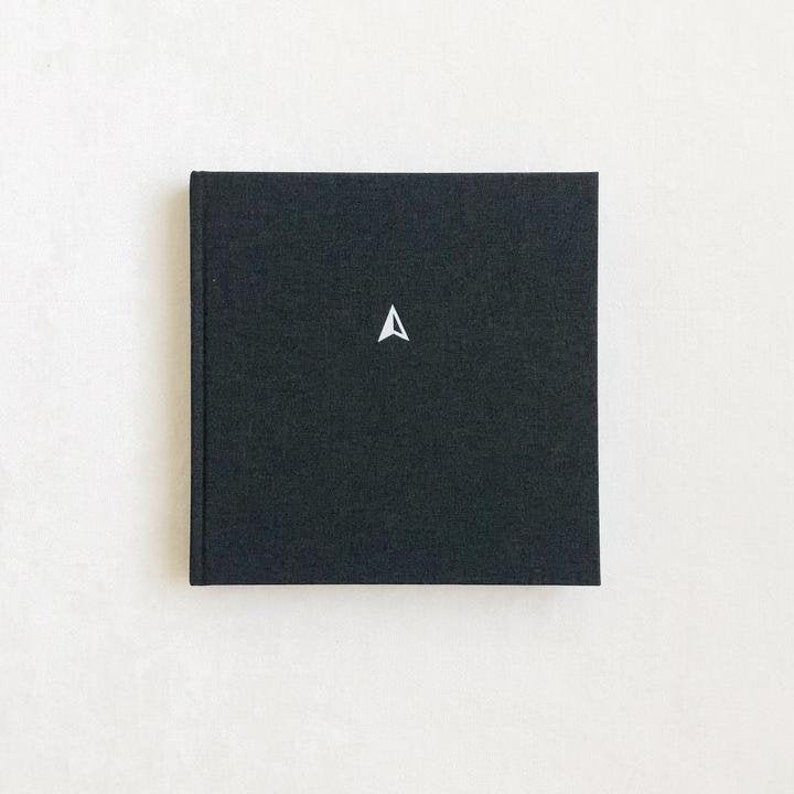 May include: A black hardcover journal with a white compass symbol on the front.