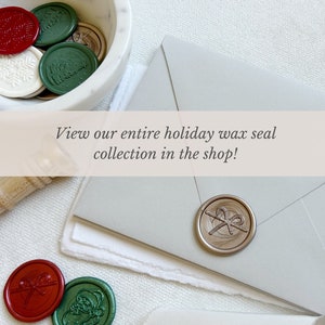 May include: A collection of holiday wax seals in a white marble bowl. The seals are in various colours, including red, green, and gold. The seals feature designs such as a snowflake, a Christmas tree, and a bow. The text "View our entire holiday wax seal collection in the shop!" is displayed on a banner above the bowl.