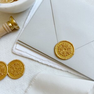 A gold wax seal snowflake on a Christmas card