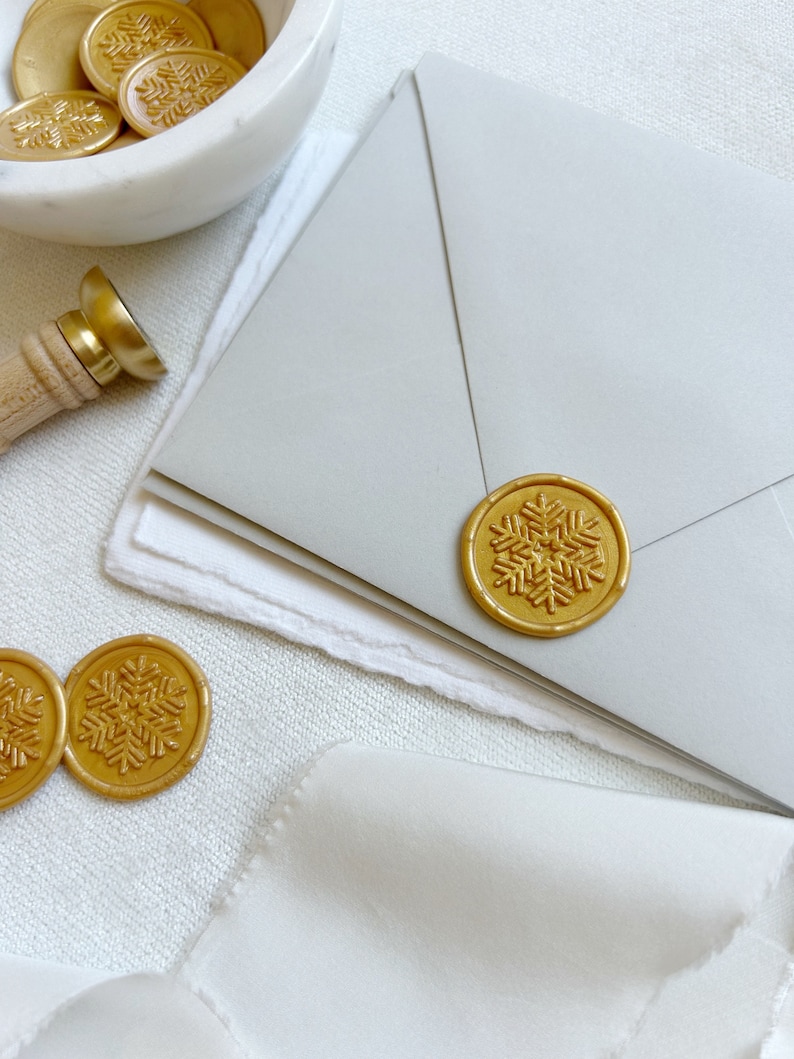 A gold wax seal snowflake on a Christmas card