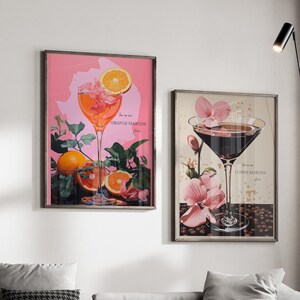 Può includere: Due stampe artistiche incorniciate raffiguranti cocktail. Una presenta un martini all'arancia con fette d'arancia e la scritta "Orange Martini". L'altra mostra un martini al caffè con fiori rosa e la scritta "Coffee Martini".