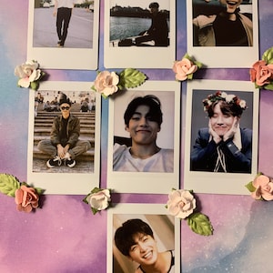 May include: A collection of seven instant photos featuring various people, arranged on a purple and white background. The photos are decorated with artificial pink and peach-colored paper roses and green leaves.