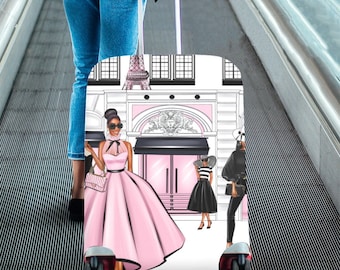 May include: A white suitcase with a colorful illustration of a Parisian street scene featuring women in stylish outfits. The suitcase has black wheels and a black handle.