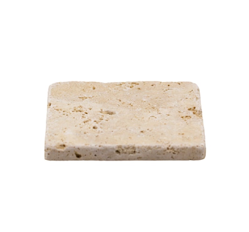 May include: A rectangular, beige-colored stone coaster with a textured surface. The coaster has a natural, porous appearance, and is likely made of travertine or a similar material. The edges are slightly rounded.