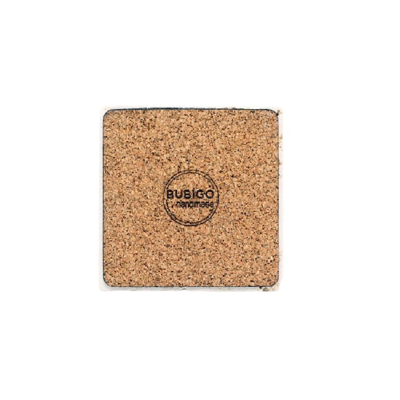 May include: Square cork coaster with a white border. The coaster has a natural brown color and a textured surface. The bottom of the coaster features a circular logo with the text "BUSIGO handmade".