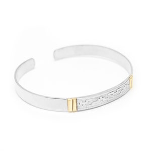 May include: Silver bangle bracelet with a textured design and two gold accents.
