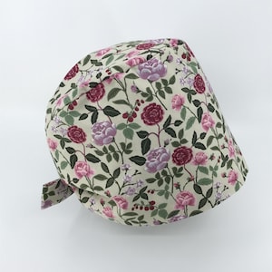 May include: A light green scrub cap with a floral pattern featuring pink and red roses, green leaves, and small white flowers.