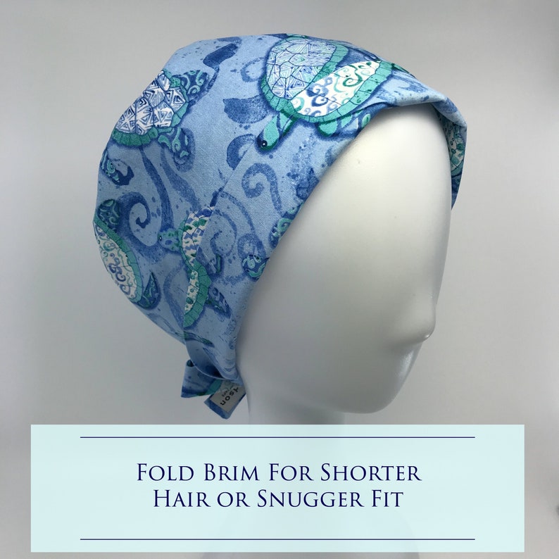 May include: Blue surgical scrub hat with a turquoise and white sea turtle pattern. The brim can be folded for a shorter hair length or a snugger fit. "Fold Brim for Shorter Hair or Snugger Fit" is written in white text on a light blue background.