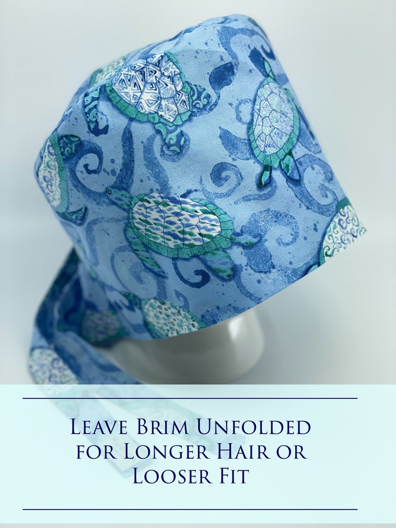 May include: A blue surgical cap with a pattern of sea turtles and swirls. The text "LEAVE BRIM UNFOLDED FOR LONGER HAIR OR LOOSER FIT" is printed on the bottom of the image.
