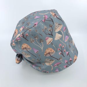 May include: A blue surgical scrub hat with a mushroom print. The mushrooms are in shades of pink, brown, and white.
