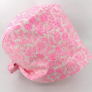 May include: A white scrub hat with a pink floral pattern. The hat has a tie on the back.