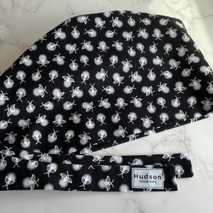 May include: A white ceramic mug with a black handle and the text "But First, Coffee" in a bold, black font. The mug is filled with a dark liquid, likely coffee, and sits on a light-colored surface.