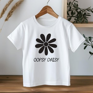 May include: White t-shirt with a black daisy graphic and the text "Oopsy Daisy" printed on the front.