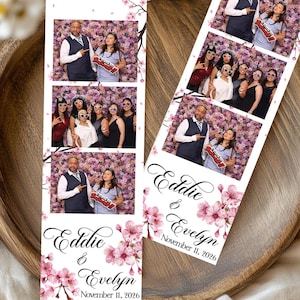 May include: Photo booth strips featuring wedding photos of Eddie and Evelyn, with a floral and cherry blossom design. The strips include the names and wedding date, with a pink and white color scheme. The background is a floral wall.