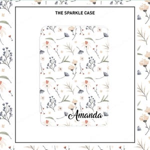 May include: A white phone case with a floral pattern in shades of pink, beige, and blue. The text "The Sparkle Case" is at the top of the case. The name "Amanda" is written in cursive at the bottom of the case.