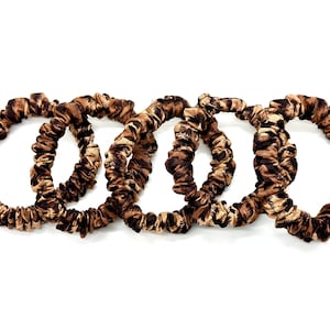 May include: Four brown and black patterned scrunchies made of silky fabric.