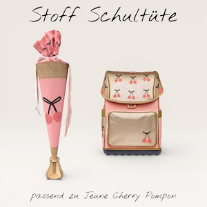 Könnte beinhalten: Ein rosa-goldener Rucksack und eine passende rosa kegelförmige Schultüte. Die Schultüte hat ein Kirschdesign und den Text "Stoff Schultüte" und "passend zu Jeune Cherry Pompon". Der Rucksack hat ein Kirschdesign.