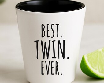 Puede incluir: Vaso de chupito blanco con borde negro, con el texto "BEST. TWIN. EVER." en negro. Una rodaja de lima verde está al lado del vaso. El vaso de chupito está sobre una superficie blanca.