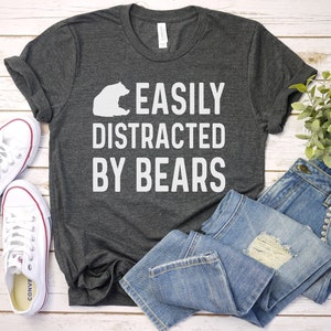 May include: A dark gray t-shirt with a white bear graphic and the text "EASILY DISTRACTED BY BEARS".