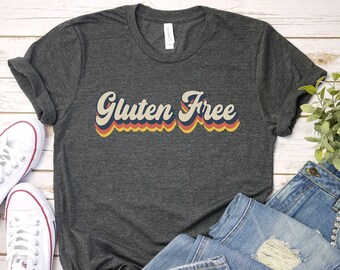 May include: A dark gray t-shirt with the text "Gluten Free" in a retro rainbow font.
