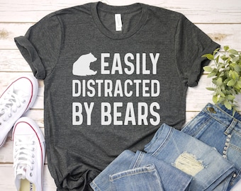 Puede incluir: Una camiseta gris oscuro con un gráfico de oso blanco y el texto "EASILY DISTRACTED BY BEARS".