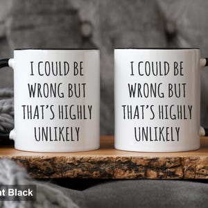 May include: Two white ceramic mugs with black handles and rims. Each mug has the text "I COULD BE WRONG BUT THAT'S HIGHLY UNLIKELY" printed in black. The mugs are 11oz in size.