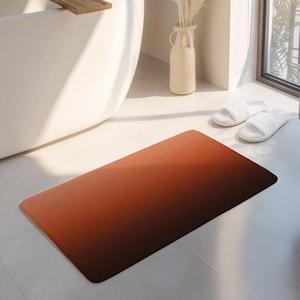 May include: A rectangular bath mat featuring a smooth gradient transition from a vibrant burnt orange on the left side to a deep, dark chocolate brown on the right side, with rounded corners and a flat, uniform surface texture throughout.