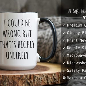 May include: White ceramic mug with a black handle and rim, featuring the text "I COULD BE WRONG BUT THAT'S HIGHLY UNLIKELY" in black. The mug is on a wooden surface. The image also includes text that says "A Gift They'll Love".