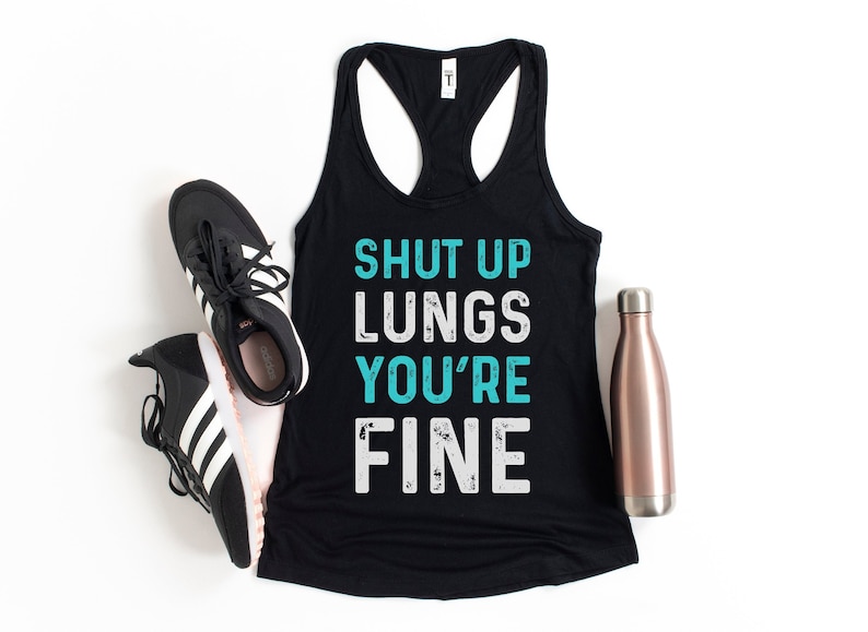 May include: Black tank top with the text "SHUT UP LUNGS YOU'RE FINE" in white and turquoise lettering. The tank top is on a white background with a water bottle and two black and white trainers.