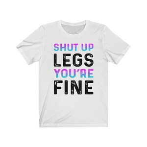 May include: White t-shirt with the text "SHUT UP LEGS YOU'RE FINE" in black with a pink and blue gradient effect.