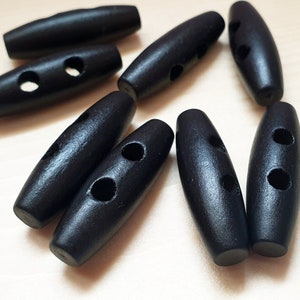 May include: A close-up of ten black wooden toggle buttons with two holes each. The buttons are oval shaped and have a smooth, polished finish.