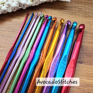 May include: A selection of metallic crochet hooks in a range of vibrant colours, displayed on a wooden surface. Sizes are marked from 2.0mm to 8.0mm. The text "AvocadoStitches" is visible. The hooks are for crafting and measure from 2.0mm to 8.0mm.