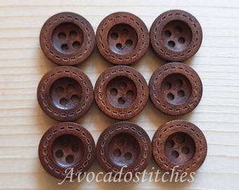 May include: Eight brown wooden buttons with a decorative design. Each button has four holes.