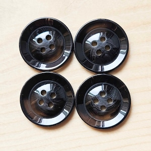 May include: Four black plastic buttons with four holes each. The buttons have a shiny, slightly textured surface.