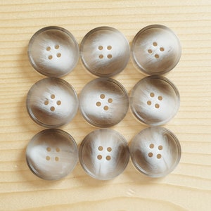 May include: Nine white and grey swirl patterned buttons with four holes each.