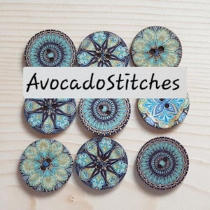 May include: Nine round buttons arranged in a grid, each featuring distinct blue, teal, and gold geometric or floral patterns. Each button has two central holes. The text "AvocadoStitches" is overlaid across the centre of the image.