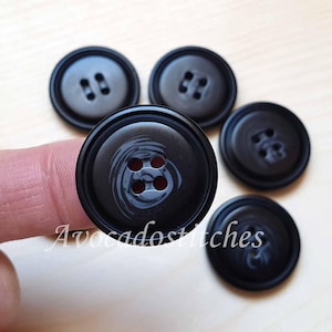 May include: Five black buttons with a swirl design. Four buttons have two holes and one button has four holes.